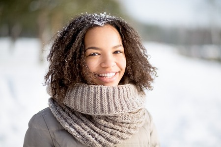 Cheerful curly African woman in winter parkの写真素材