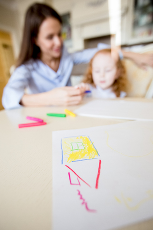 Childish drawing of house on table and familyの写真素材