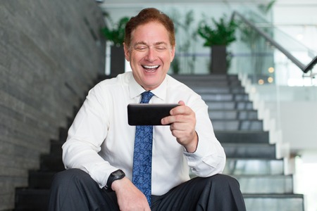 Senior businessman laughing at internet videoの写真素材