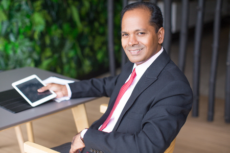 Happy Indian Business Man Using Tablet in Cafeの写真素材