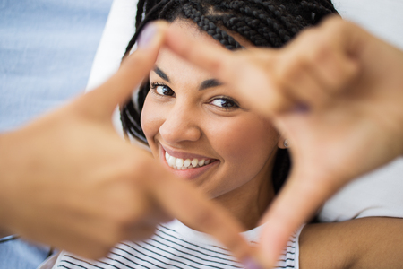 Smiling young woman making frame with fingers