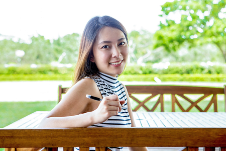 Cheerful Asian female student sitting outdoorsの写真素材