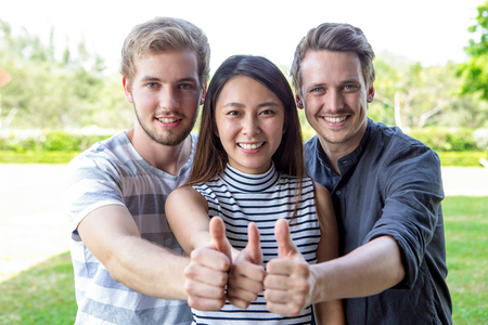 Three successful student friends showing thumbs up