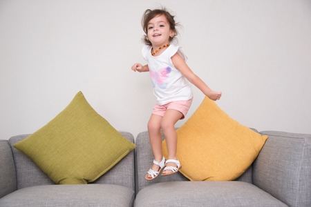 Carefree girl jumping on sofaの写真素材
