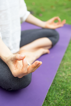 Hand of young woman practicing yoga on mat outdoorの写真素材