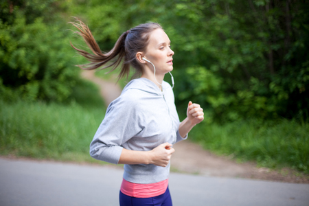 Concentrated young woman jogging with earphonesの写真素材