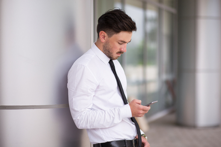Busy manager checking mail near office buildingの写真素材