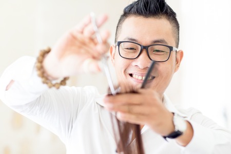 Smiling young Asian hairdresser working with hairの写真素材