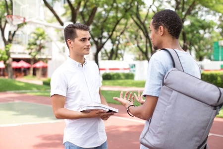Serious young male students talking in campusの写真素材