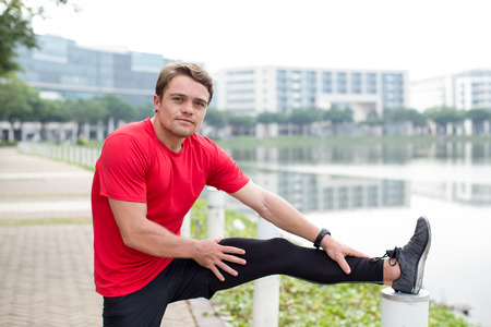 Content Sporty Man Stretching Leg Outdoorsの写真素材