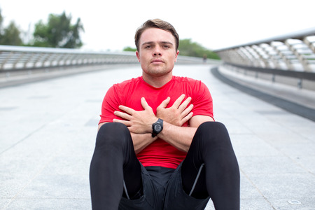 Serious Young Sportsman Doing Sit-ups Outdoorsの写真素材