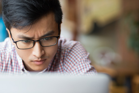Concentrated man in glasses looking at screenの写真素材