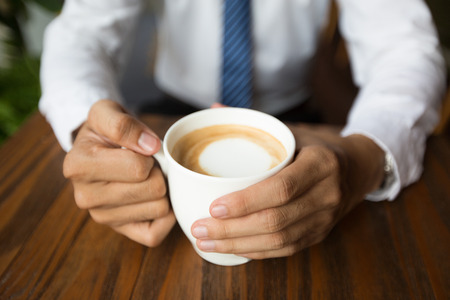 Close-up of male hands holding coffee cupの写真素材
