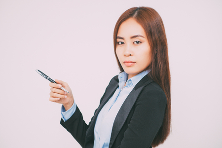 Serious Asian woman with pen looking at cameraの写真素材