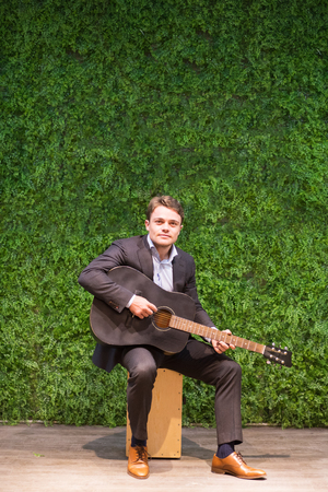 Beginning musician in suit playing guitar
