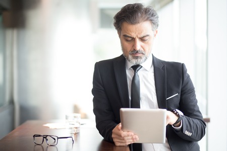 Concentrated senior businessman using tabletの写真素材