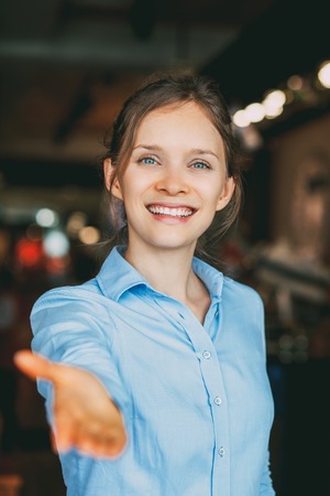 Cheerful businesswoman reaching hand to cameraの写真素材
