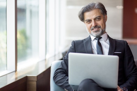 Cheerful successful businessman working in lobbyの写真素材