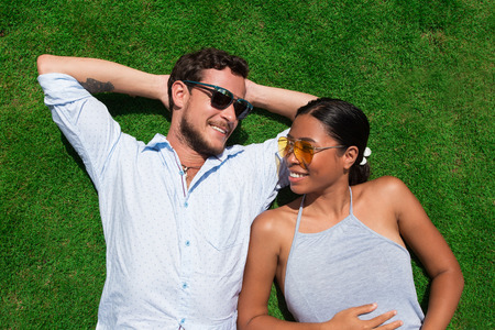 Happy Young Multi-ethnic Couple Resting on Lawnの写真素材