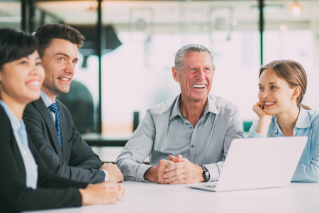 Cheerful businesspeople sitting in boardroomの写真素材