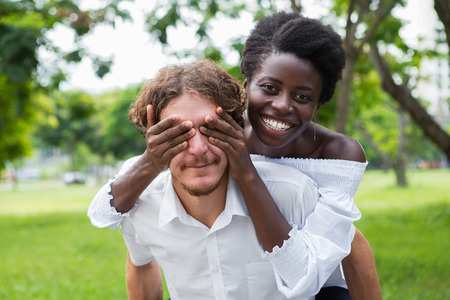 Joyful girlfriend covering eyes of man in park