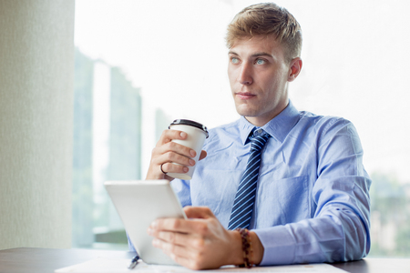 Serious Business Man Using Tablet and Drinkingの写真素材