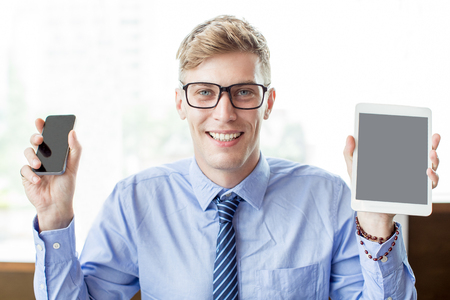 Smiling Business Man Showing Tablet and Smartphoneの写真素材