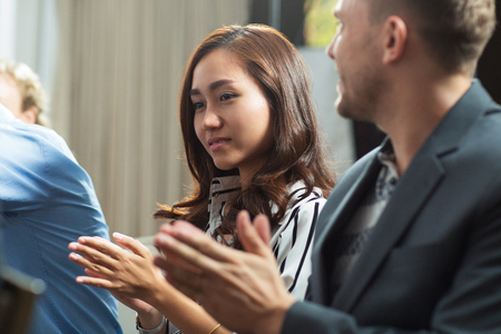 Smiling Asian businesswoman clapping at conferenceの写真素材