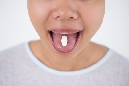 Cropped View of Woman Holding Pill on Tongueの写真素材