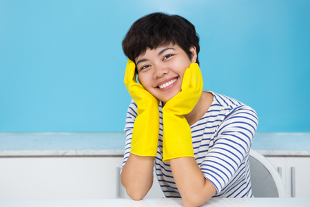 Smiling Housewife in Protective Gloves in Kitchenの写真素材