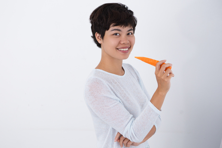 Smiling Young Asian Woman Holding Carrotの写真素材