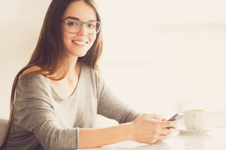Portrait of cheerful young woman with mobile phoneの写真素材
