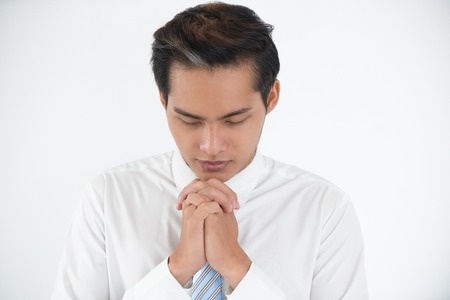 Portrait of silent young Asian businessman prayingの写真素材
