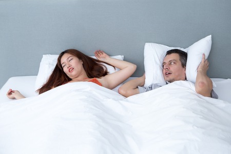 Snoring Woman and Husband Covering Earsの写真素材