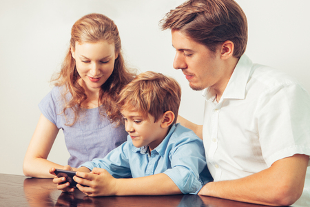 Boy Playing Game on Smartphone and Parentsの写真素材