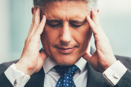 Portrait of stressed businessman touching his headの写真素材