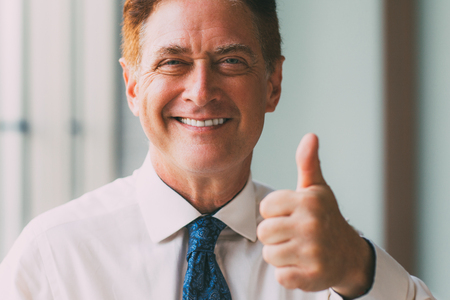 Happy mature businessman showing thumb upの写真素材
