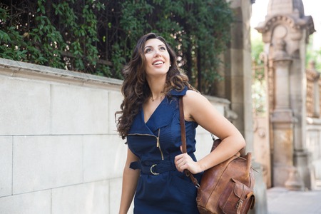 Excited female traveler walking and looking upの写真素材