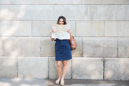 Happy female traveler consulting map in streetの写真素材