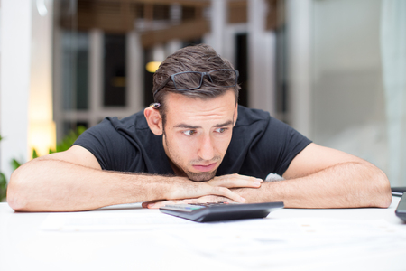 Frustrated Man Lying on Desk With Calculatorの写真素材