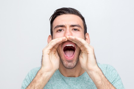 Young Man Cupping Hands and Shouting Loudの写真素材