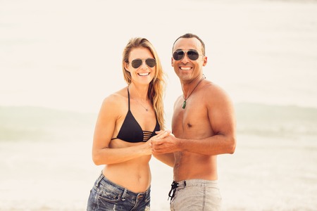 Portrait of cheerful couple holding hands on beachの写真素材
