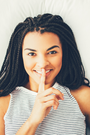Smiling African-American woman with finger on lipsの写真素材