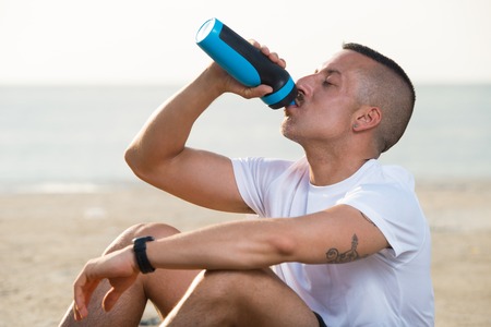 Relaxed young man drinking water from bottleの写真素材