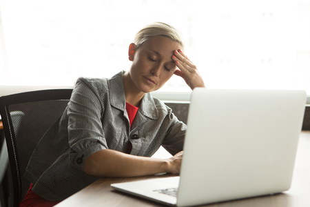 Portrait of tired businesswoman sitting at laptopの写真素材