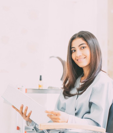 Happy woman with braces sitting in hair salonの写真素材