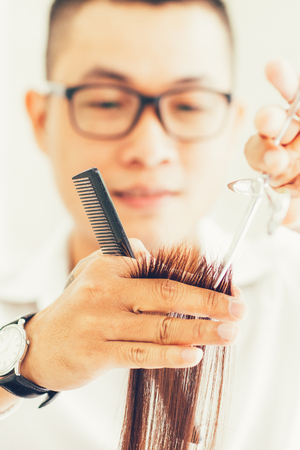 Serious hairdresser cutting hair with scissorsの写真素材