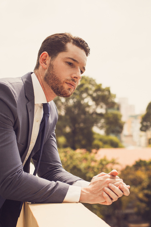 Thoughtful Business Man Leaning on Railing Outsideの写真素材