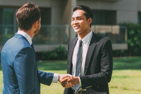 Two Smiling Partners Shaking Hands Outdoorsの写真素材