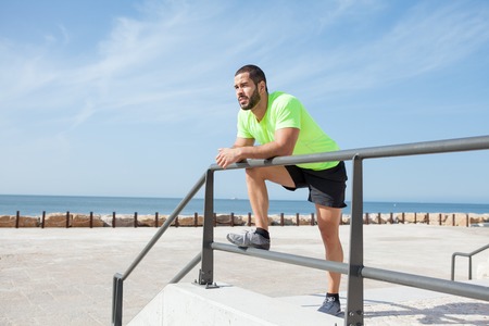 Pensive Sporty Man Relaxing and Leaning on Railing
